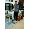 A woman is using a cordless vacuum cleaner in a living room. Produktbild-Vorschau