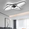 A modern geometric LED ceiling light fixture with multiple rings, installed on a white ceiling in a living room setting. Podgląd zdjęcia produktu