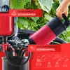 A person is holding a red and black submersible pump over a water barrel, with green grapevines in the background. Produktbild-Vorschau
