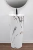 A pedestal sink with a marble-like pattern and a black faucet, set against a white wall and a wooden floor. Produktbild-Vorschau