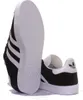 A pair of black Adidas Gazelle sneakers with white accents, shown from a low angle with the sole of one shoe prominently displayed. Produktbild-Vorschau