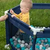 A baby playing in a ball pit outdoors. Produktbild-Vorschau