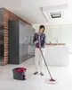A woman is cleaning a modern kitchen floor with a spin mop and bucket. Produktbild-Vorschau