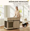 A woman is standing next to a wooden dog crate with sliding doors and drawers, demonstrating its mobility with wheels. Náhled obrázku produktu