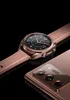 A close-up studio shot of a bronze Samsung Galaxy Watch 3 and a bronze Samsung Galaxy smartphone, both with a black background. Náhled obrázku produktu