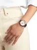 A close-up shot of a woman's wrist wearing a watch, with her hand resting on her lap, wearing light-colored jeans. Produktbild-Vorschau