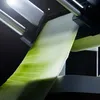 A close-up shot of a green vegetable being sliced by a peeler. Produktbild-Vorschau