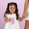 A young girl in a white dress holds a pink cup while holding hands with an adult. Produktbild-Vorschau