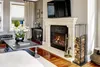 A living room with a fireplace, a coffee table, and a wood rack. Produktbild-Vorschau