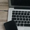 A close-up view of a laptop keyboard and a smartphone resting on a wooden surface. Voir les images du produit