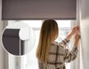 A woman is adjusting a roller blind in a room. Anteprima dell’immagine prodotto