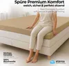 A person sitting on a bed with a fitted sheet. Produktbild-Vorschau