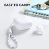 A white charging case and one earbud are placed on a white surface next to a notebook and keys. Produktbild-Vorschau
