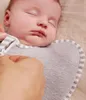 A close-up shot of a sleeping baby swaddled in a gray and white striped swaddle. Produktbild-Vorschau