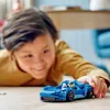 A child is playing with a blue LEGO car on the floor. Podgląd zdjęcia produktu