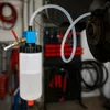 A brake bleeding device connected to a car's brake caliper in a workshop setting. Produktbild-Vorschau