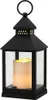 A black metal lantern with a lit LED candle inside, set against a white background. Náhled obrázku produktu