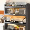 A kitchen cabinet with various appliances and dishes stored inside. The cabinet has a transparent door that is partially open, revealing the contents. Anteprima dell’immagine prodotto