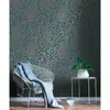 A chair with a blanket and a plant next to a wall with floral wallpaper. Náhľad obrázku produktu