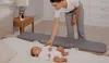 A woman is placing a baby bed rail on a bed next to a baby. Voir les images du produit