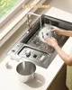 A person is washing a part of a kitchen appliance in a sink. Produktbild-Vorschau