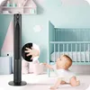 A baby crawling on the floor in a nursery, reaching towards a tall black fan. Náhled obrázku produktu
