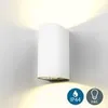 A white cylindrical wall light emitting light upwards and downwards against a light gray wall. Náhled obrázku produktu