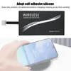 A hand is holding a smartphone over a wireless charging pad, with a wireless charging receiver attached to the phone. Produktbild-Vorschau
