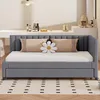 A gray daybed with a white mattress and two pillows on it, placed on a rug with a geometric pattern. In the background, there is a white counter with some decorative items and kitchen appliances. Náhľad obrázku produktu