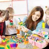 A teacher or parent is showing children a craft project, with various craft supplies spread on a table. Produktbild-Vorschau