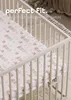 A close-up view of a crib with a fitted sheet featuring a space-themed pattern of bears and rockets. Produktbild-Vorschau