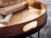 A close-up shot of a hammered gold tray with a black base, featuring a book and a framed picture on it. Voir les images du produit
