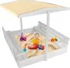 A baby playing in a wooden sandbox with toys under a canopy. Podgląd zdjęcia produktu