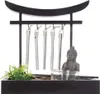 A zen garden decorative item with a Buddha statue, wind chimes, and plants. Anteprima dell’immagine prodotto