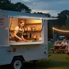 A food truck serving customers outdoors in the evening, with string lights and picnic tables. Produktbild-Vorschau