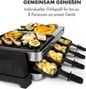 A raclette grill with food being cooked on it and in the raclette pans. Produktbild-Vorschau