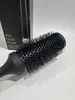 A close-up shot of a black round hair brush with its bristles facing the viewer, with a black box in the background. Podgląd zdjęcia produktu