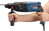 A person's hands are holding a blue and black Bosch rotary hammer drill. Podgląd zdjęcia produktu
