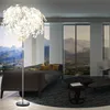 A modern living room with a large window overlooking a mountain landscape, featuring a sofa, coffee tables, and a floor lamp. Produktbild-Vorschau