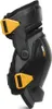 A black and yellow knee pad is shown against a white background. Voir les images du produit