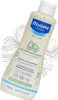 A bottle of Mustela Gentle Shampoo is shown at an angle against a background with abstract wavy lines. Podgląd zdjęcia produktu