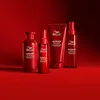 A collection of Wella Professionals Ultimate Repair hair products arranged on a red surface against a red background. Náhľad obrázku produktu