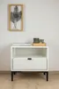 A white nightstand with a drawer and an open shelf, decorated with a framed leaf artwork on the wall above it and a small tray with decorative items on top. Produktbild-Vorschau