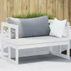 A white wooden garden bench with two cushions, one gray and one white, placed on a tiled patio with a wooden fence and grass in the background. Náhled obrázku produktu