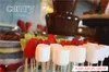 A chocolate fountain with various fruits and marshmallows on skewers in the foreground. Podgląd zdjęcia produktu