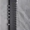 A close-up view of a modern black shower panel with multiple water jets spraying water. Náhled obrázku produktu