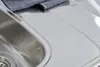 A close-up view of a stainless steel kitchen sink and countertop. Produktbild-Vorschau