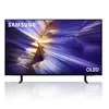 A Samsung OLED TV is displayed on a white reflective surface with its stand. Produktbild-Vorschau