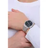 A person wearing a white long-sleeved shirt and a watch on their left wrist. Voir les images du produit