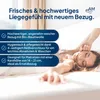 A woman is lying on a bed, stretching her arm. Produktbild-Vorschau